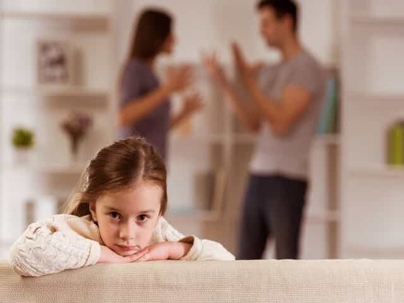Child Looking Sad with Parents Fighting in the Background